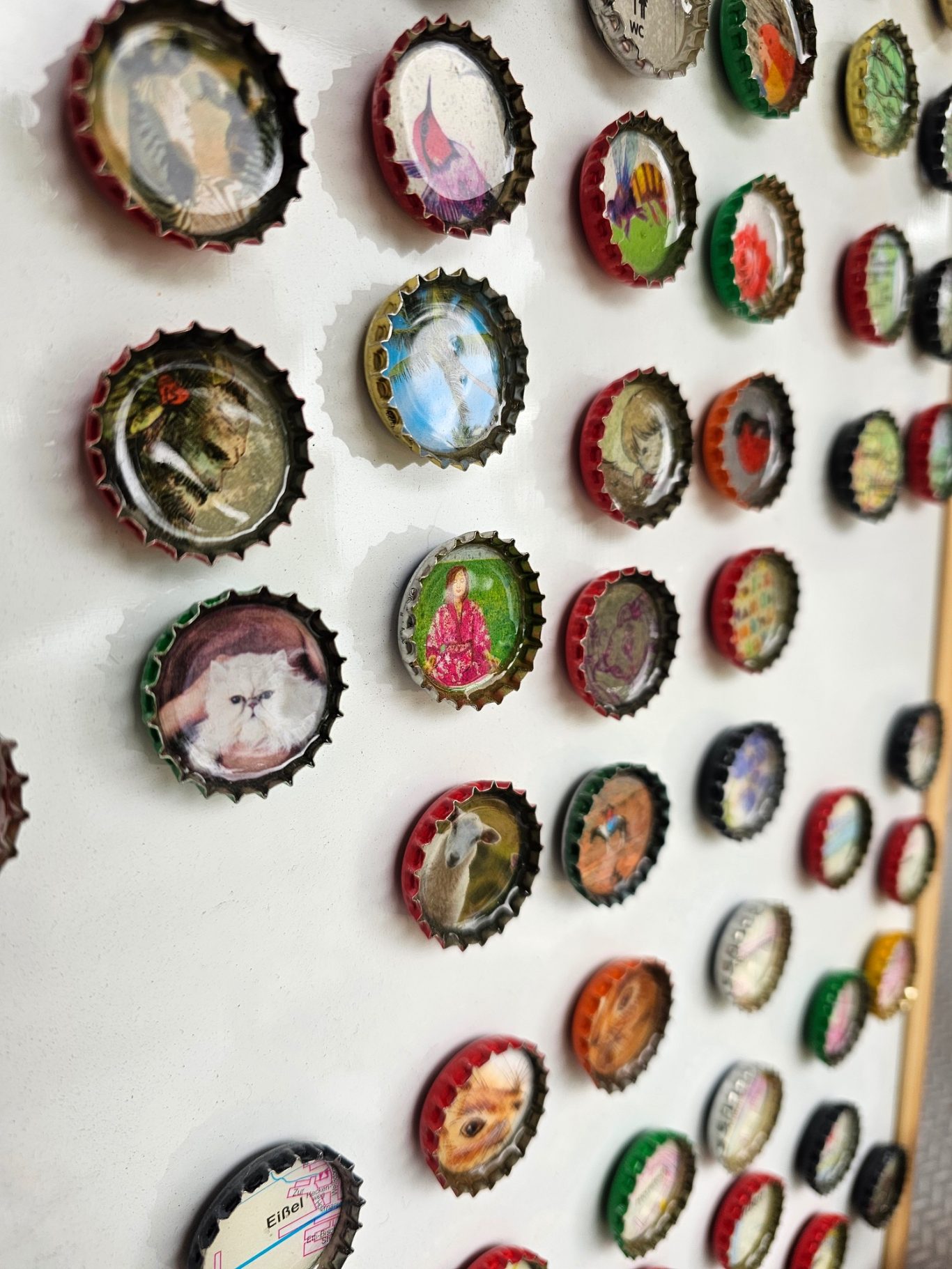 Upgecycelter Kronkorkenmagnet Eine Sammlung von bunten Kronkorkenmagneten mit verschiedenen Illustrationen.