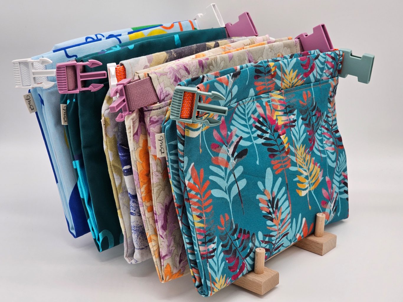 Wetbag Bunte, gemusterte Wetbag-Taschen in verschiedenen Farben auf einem Ständer.