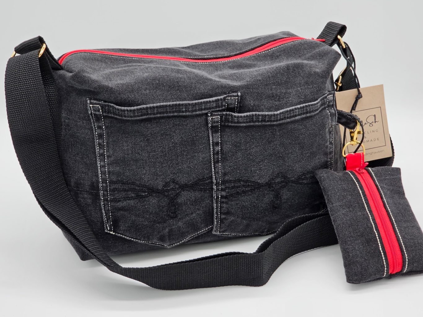 Upgecycelte Jeanstasche Schwarze Umhängetasche mit rotem Reißverschluss und zwei vorderen Taschen.