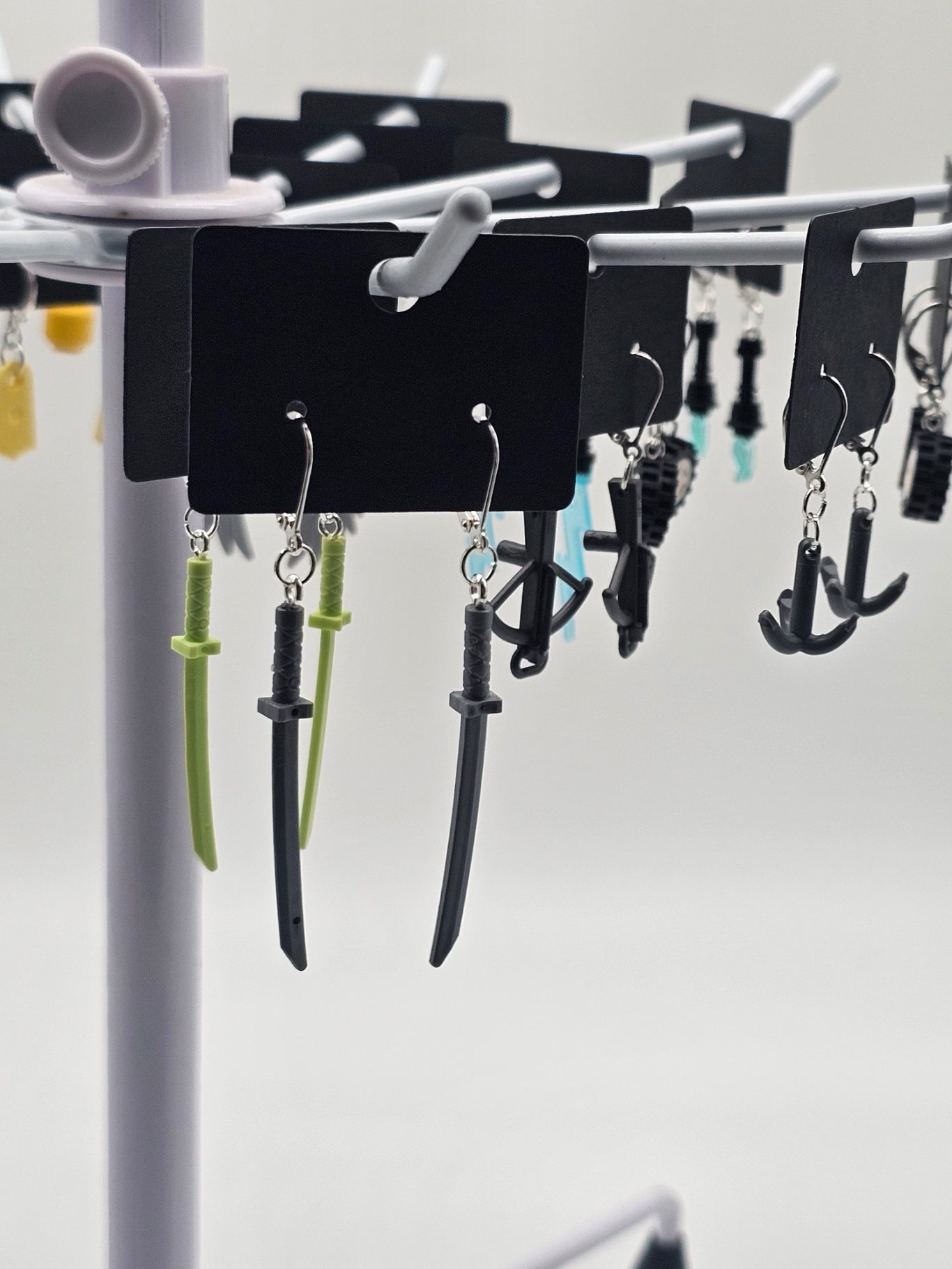 Upgecycelte Ohrringe (925er Silber) Schmuckständer mit verschiedenen Lego-Ohrringen, darunter Anker und schwertähnliche Designs.