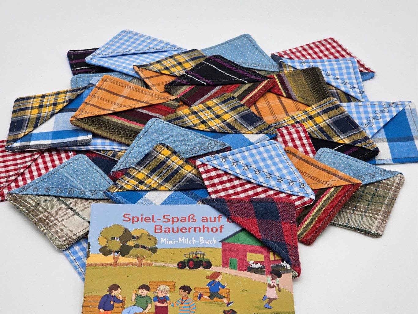 Upgecycelte Leseecke Bunte Stoffleseecken und ein Pixibuch mit einer Leseecke auf einem weißen Hintergrund.