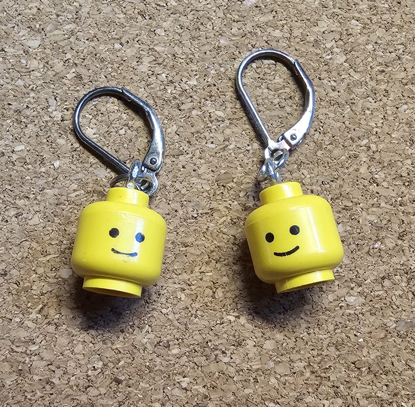 Upgecycelte Ohrringe (925er Silber) Gelbe Lego-Kopf-Ohrringe mit lächelndem Gesicht, an silbernen Haken befestigt.