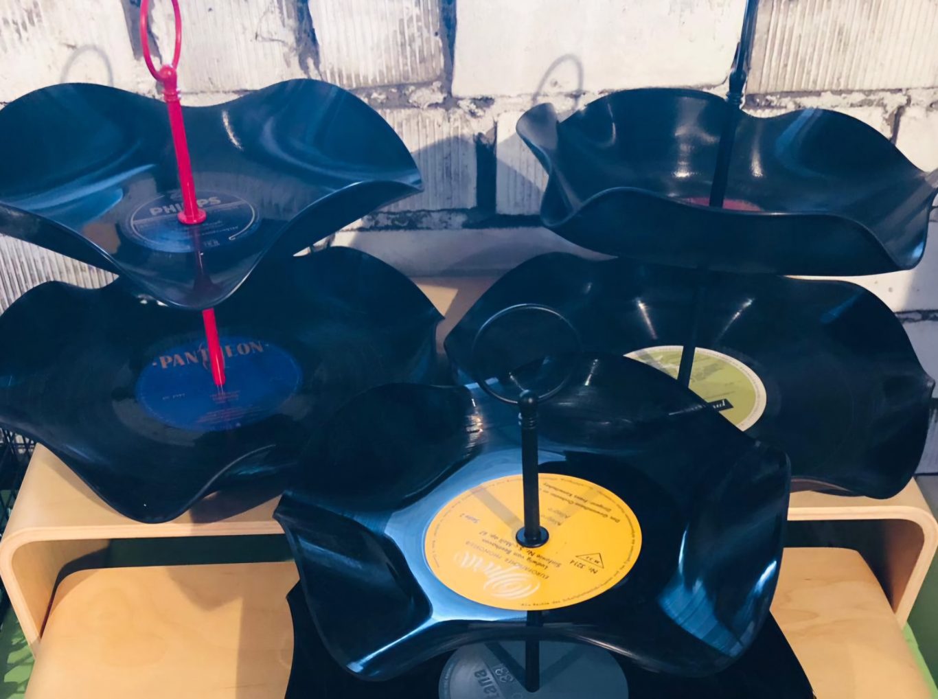 Upgecycelte Schallplattenetagere Drei Servierplatten aus Schallplatten in Schwarz mit bunten Mittelpunkten.