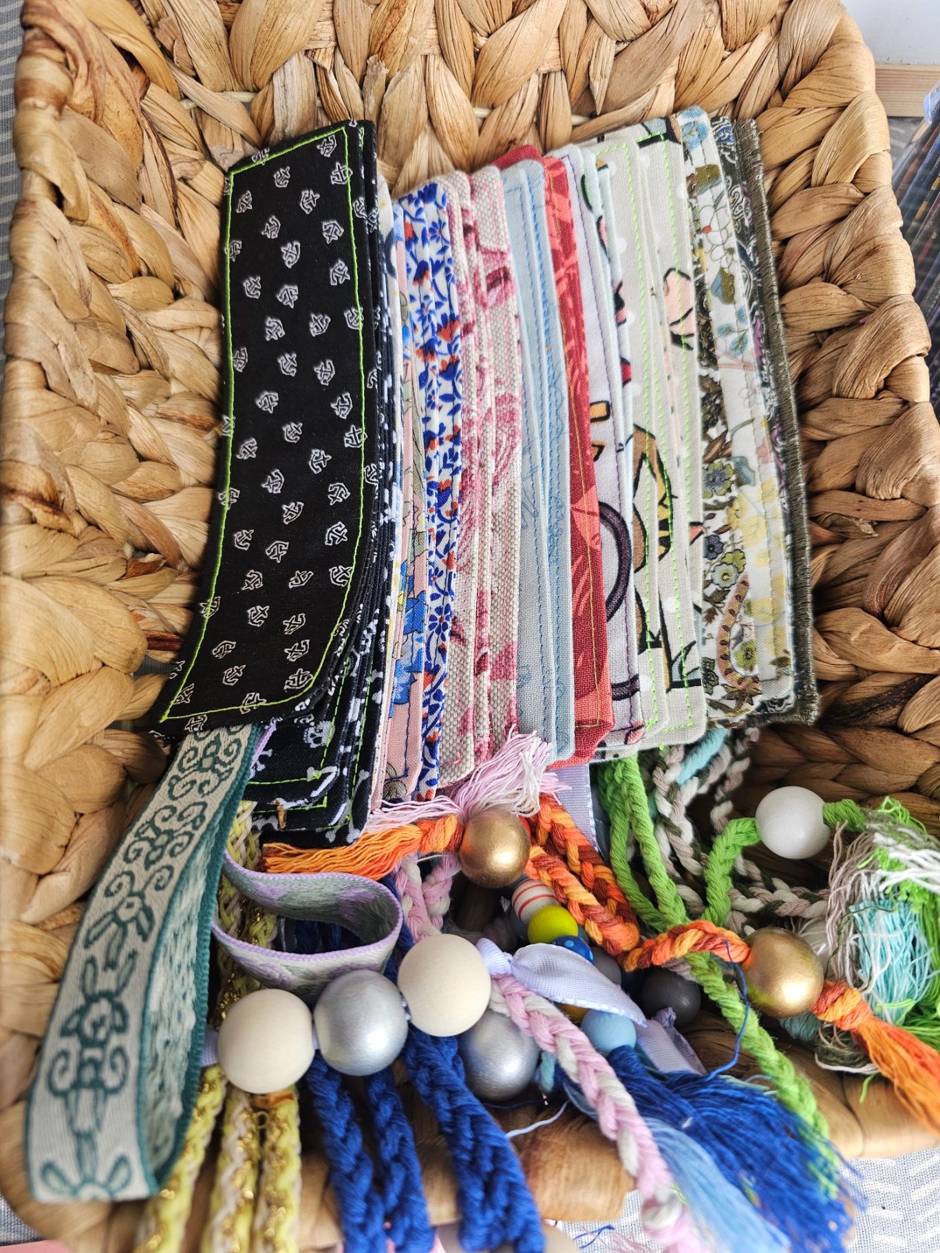 Upgecyceltes Lesezeichen Bunte Stofflesezeichen mit Bändern in einer geflochtenen Schale arrangiert.