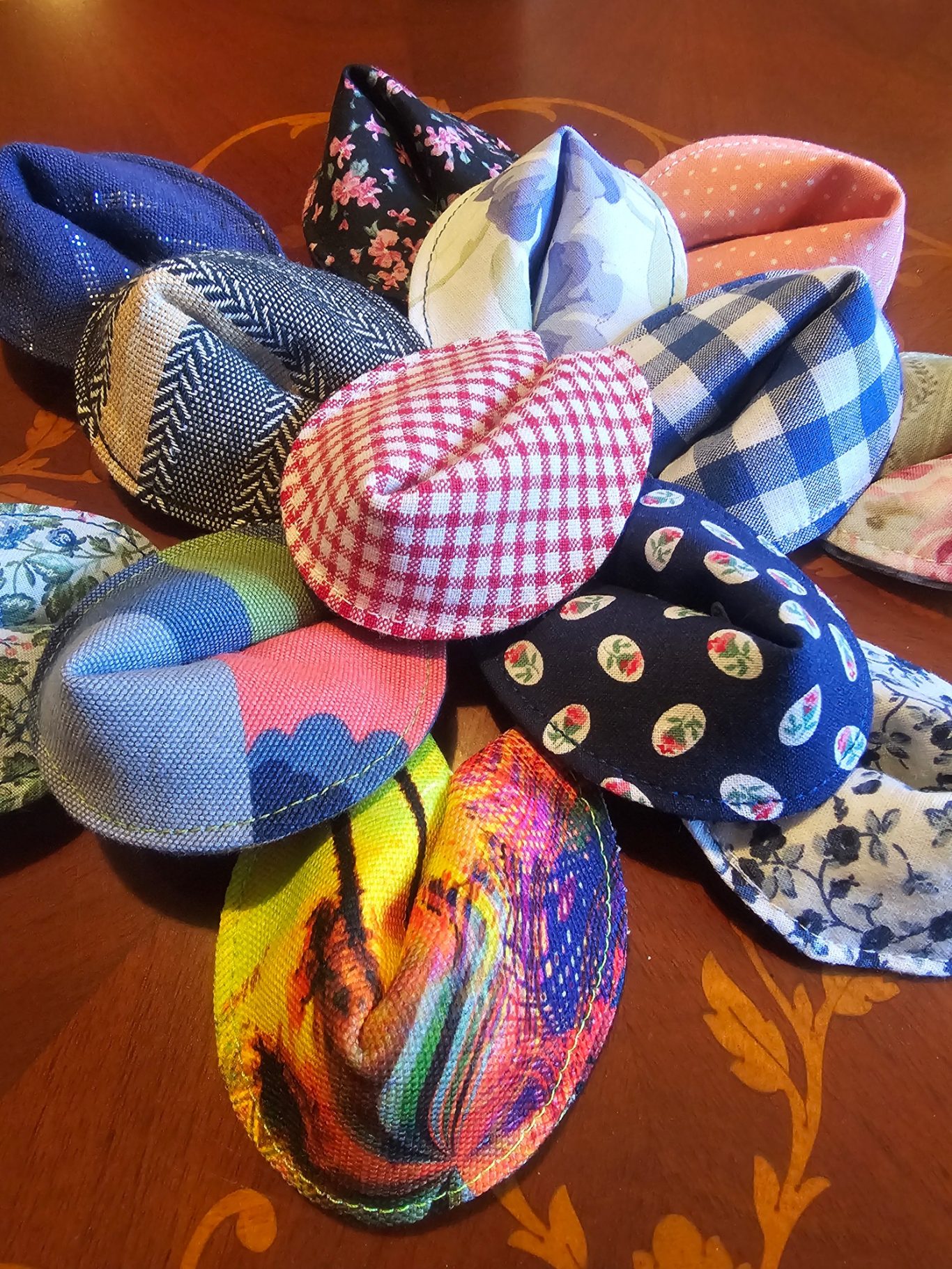 Upgecycelte, nachhaltige Glückskeks Eine Sammlung von bunten Glückskeksen aus Stoff in verschiedenen Mustern, angeordnet wie eine Blüte.