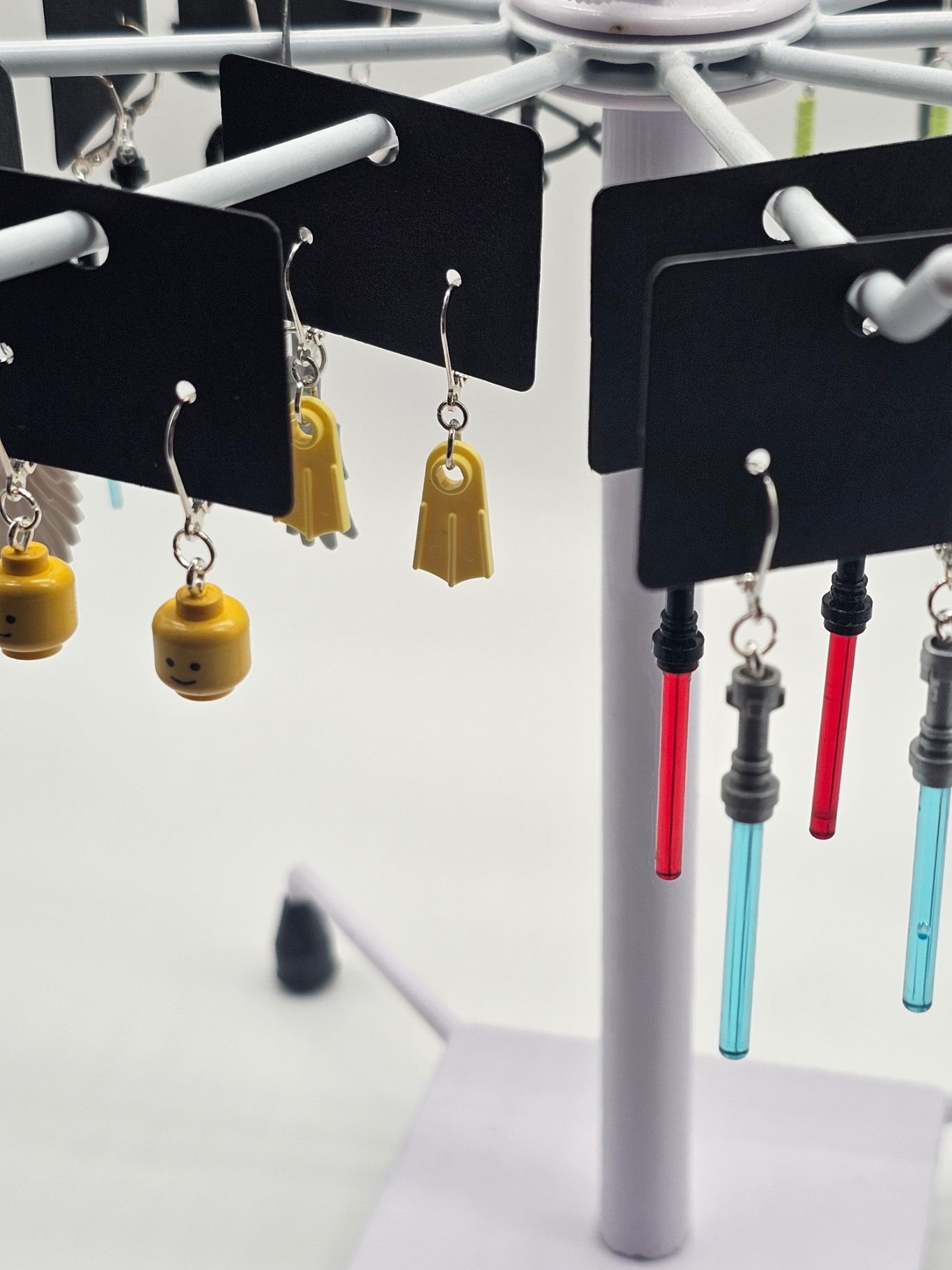 Upgecycelte Ohrringe (925er Silber) Bunte Lego-Ohrringe in verschiedenen Formen hängen an einem Ständer.