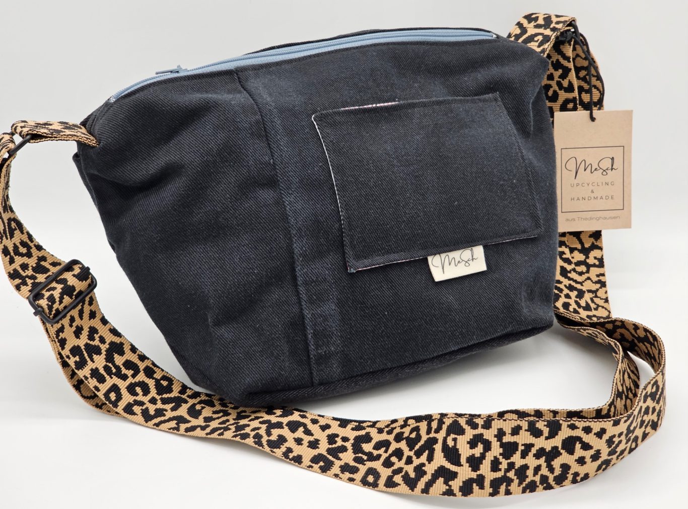 Upgecycelte Jeanstasche Schwarze Umhängetasche mit Leopardenmuster am Tragriemen und einer vorderen Tasche.
