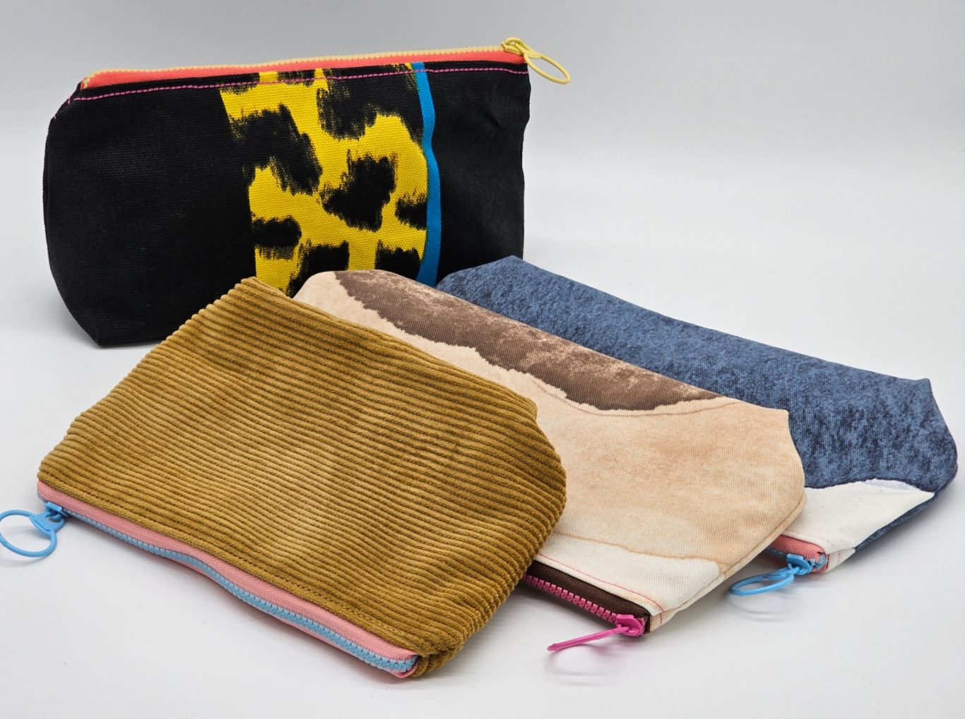 Upgecycelte Mäppchen Eine Reihe von bunten Taschen in verschiedenen Farben und Materialien, inklusive Tiermuster.