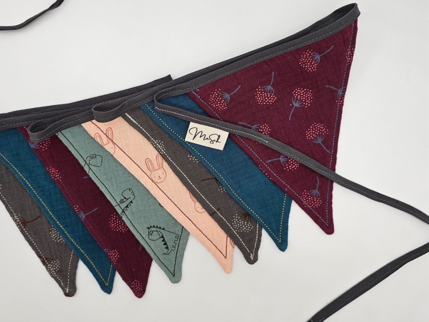 Upgecycelte Wimpelkette Bunte Wimpelkette in verschiedenen Farben und Mustern mit einem Etikett.