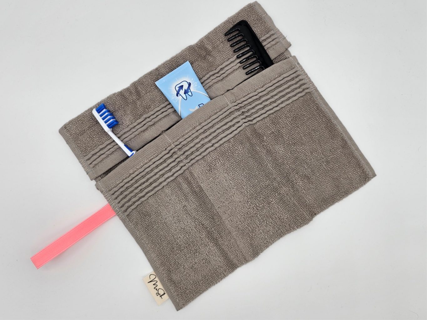 Upgecyceltes Reiseutensilio Grau gestaltetes Reiseutensilio mit verschiedenen Fächern und einen pinke Gummi zu schließen.