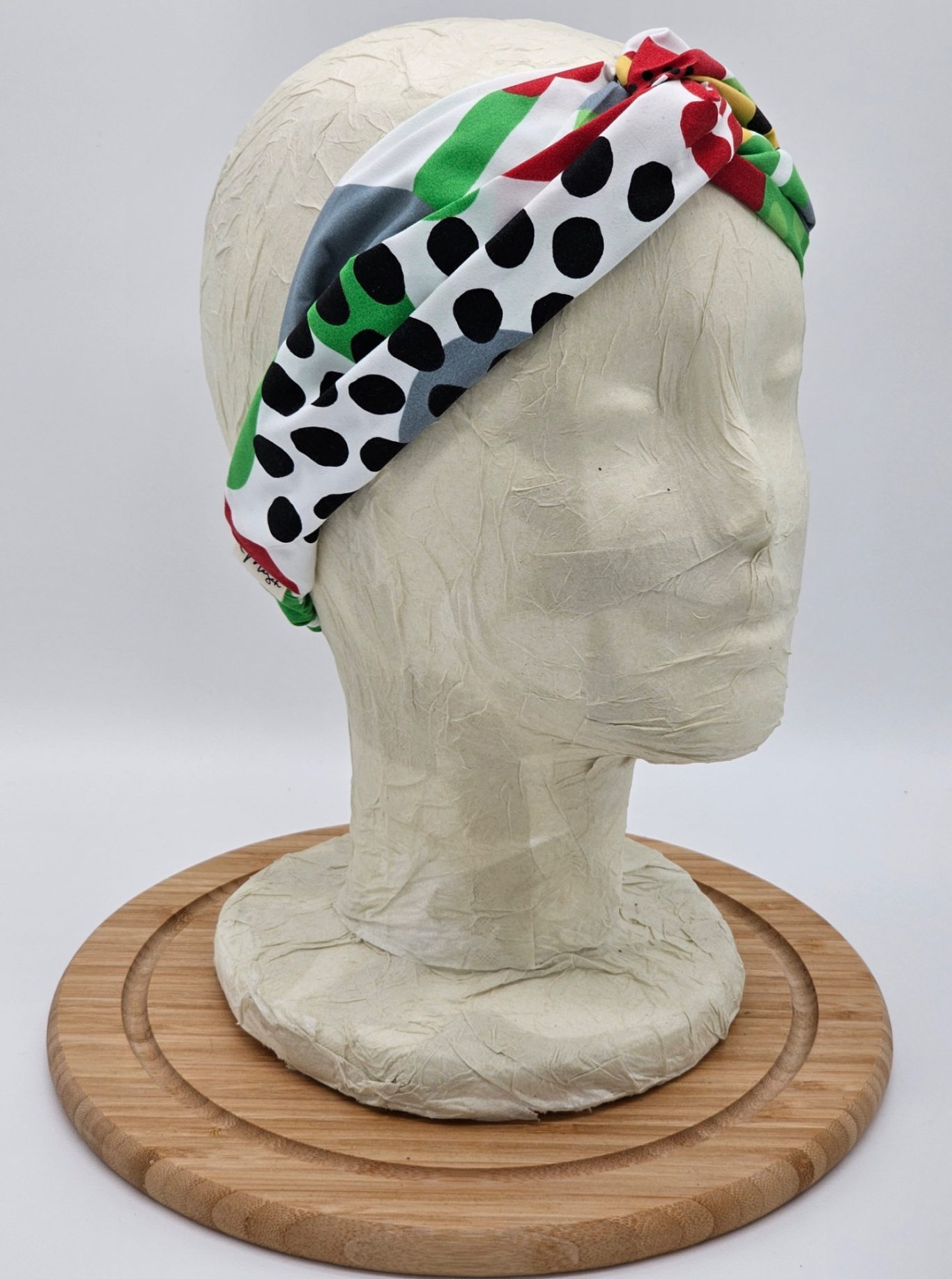 Upgecyceltes Haarband Stirnband mit buntem Muster aus Punkten und Streifen auf einem Kopfmodell.