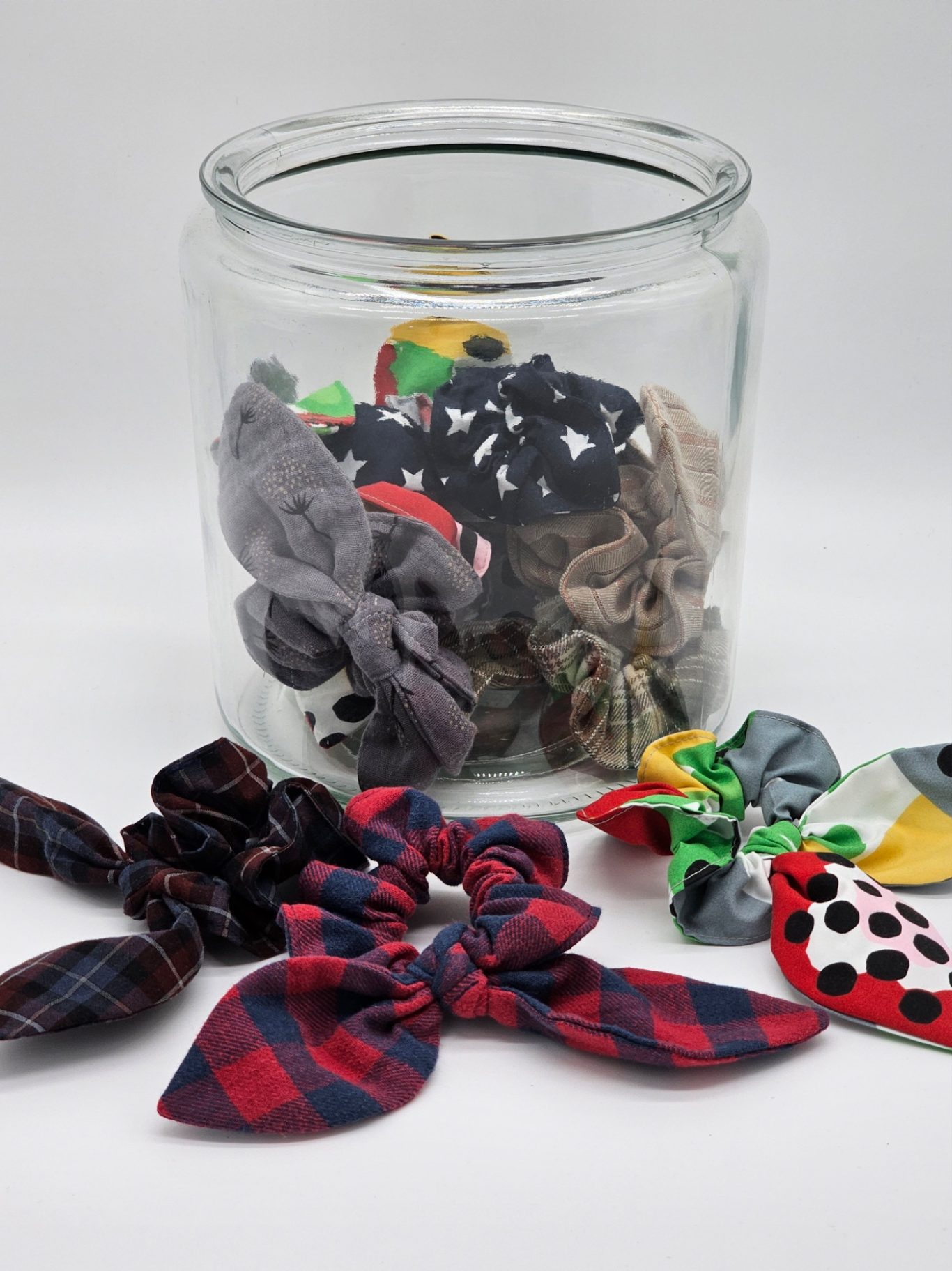Upgecyceltes Scrunchie (Haargummi) Ein Glas mit Scrunchies (Haargummis) in verschiedenen Farben und Stilen, einige liegen davor.